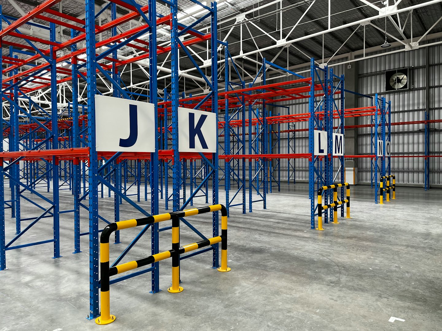 Rows of empty blue and red pallet racking in a warehouse.